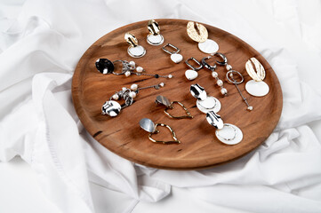 Jewelry on a wooden podium. Set of stylish silver and gold earrings with pendants and pearls