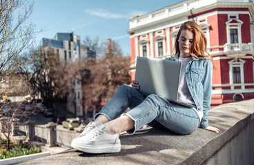 Cute caucasian long-haired woman using laptop in the city