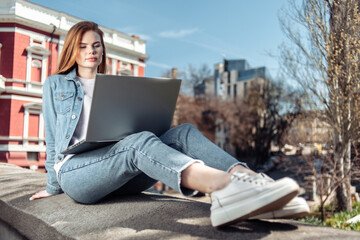 Cute caucasian long-haired woman using laptop in the city