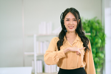 Asian female call center agent standing and use sign language with smiling face portrait in office