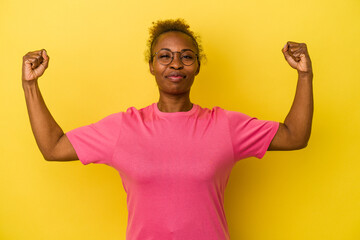 Fototapeta premium Young african american woman isolated on yellow background showing strength gesture with arms, symbol of feminine power