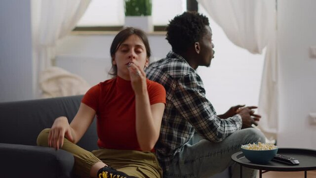 Interracial couple shouting at each other having argument in living room. Angry multi ethnic people fighting about marriage issues while sitting together on couch at home. Irritated lovers