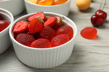 Delicious gummy candies and fresh fruits on white wooden table, closeup