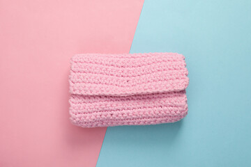 Hand made knitted pink wallet on blue pink pastel background