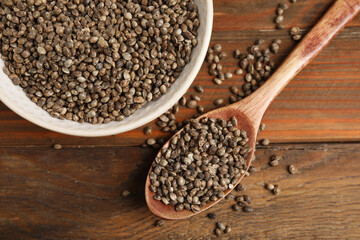 Bowl and spoon with organic hemp seeds on wooden table, flat lay