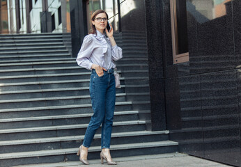 Fototapeta premium Modern business woman talking on the phone while standing on stairs