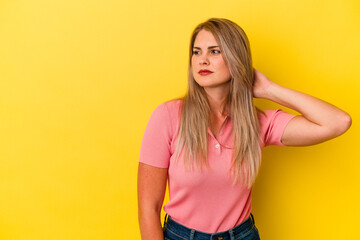Young russian woman isolated on yellow background touching back of head, thinking and making a...