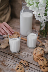 Woman hands holding jar of milk. Pouring milk in glass of milk. Homemade almond cookies with copy space for text .Crispy cookie. Food concept. Selective focus. Vintage style