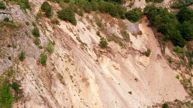 Soil erosion on a steep slope due to landslide. Surface ground movement on unstable hillside. Coastal land deterioration and collapse. Aerial drone view.