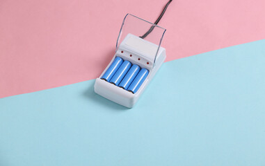 Battery charger with AA rechargeable batteries on blue pink pastel background