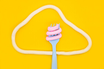 Spaghetti-shaped marmalade fork with design on yellow background. Appetizing photo. Food art