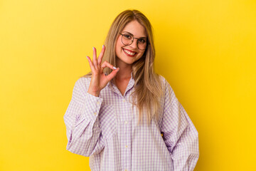 Young russian woman isolated on yellow background cheerful and confident showing ok gesture.