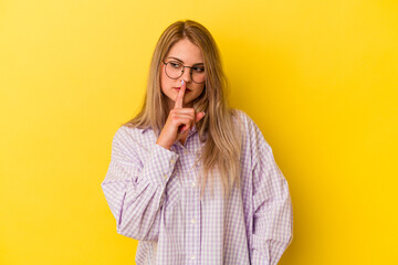 Young russian woman isolated on yellow background keeping a secret or asking for silence.