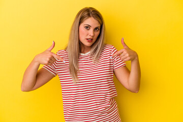 Young russian woman isolated on yellow background points down with fingers, positive feeling.