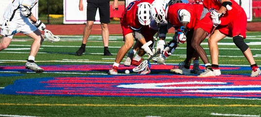 Lacrosse players fighting to scoop up the ball during a game