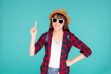 Beautiful portrait young asian woman wear sunglasses and hat smile and enjoy in summer gesture presenting and pointing something isolated on blue background, tourist girl in vacation travel concept.