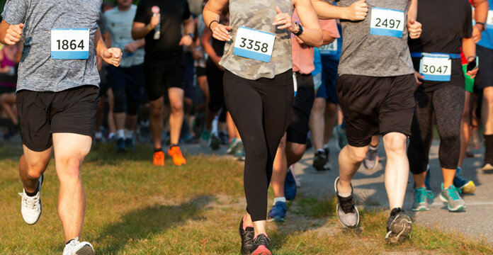 Runners running a 5K in a crowded race on grass in a park