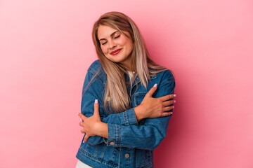 Young russian woman isolated on pink background hugs, smiling carefree and happy.