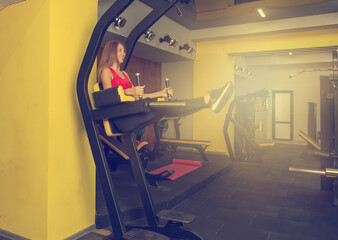 Fit slim woman in sports clothes is practicing lifting the legs for the abdominal muscles in the gym