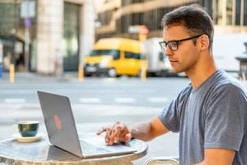 Young latin man enjoying working with computer outside.