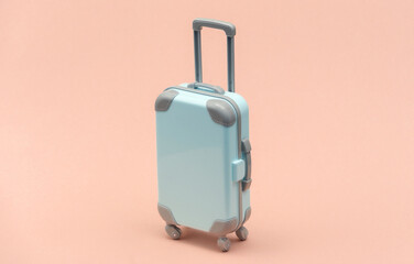 Travel or trip concept. Mini plastic travel suitcase on pink background. Minimal style