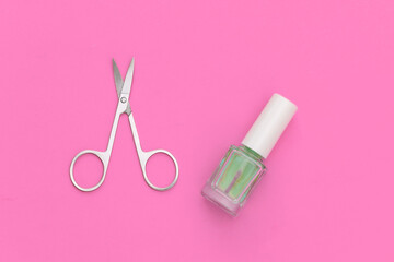 Nail polish and manicure scissors on pink background. Beauty concept. Top view