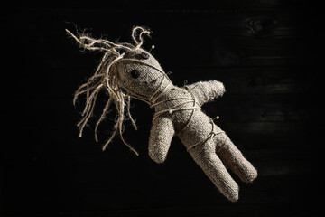 Female voodoo doll with pins on dark background