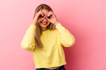 Young russian woman isolated on pink background showing okay sign over eyes