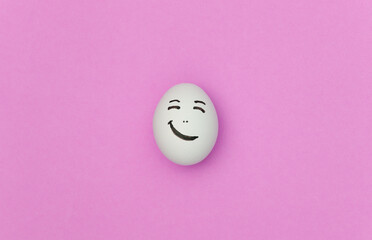 Fototapeta na wymiar Chicken egg with hand drawn happy face on pink background.