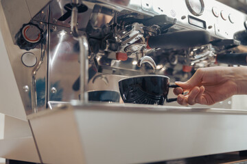 Female barista making fresh espresso in cafeteria