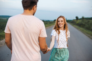 Couple holding hand and walking on road. Beautiful ginger woman with freckles. Love concept