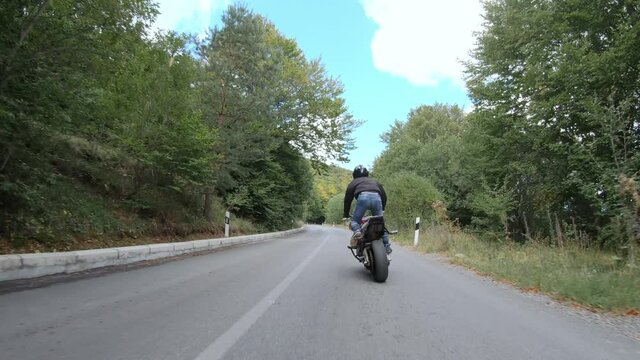 Fast motorcycle stunt road riding. having fun driving dangerous wheelie on mountain rural road