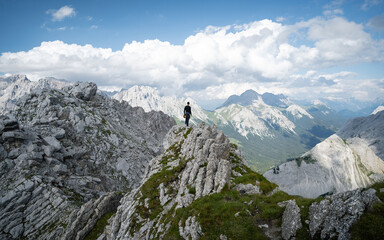 Fototapeta na wymiar Adventurous man is standing on top of the mountain and enjoying the beautiful view. Taken from mountain Tajakopf near Leermos ehrwald Austria alps