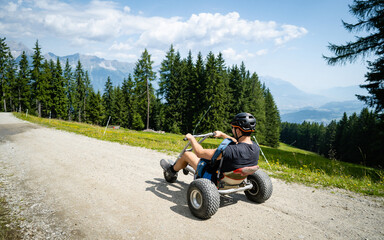 Riding a tricycle down a hill. Alpine meadow in the European Alps. During the summer guests can...