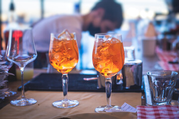 Bartender in front of beautiful row of different coloured alcohol cocktails on a party in a bar, martini, vodka, and others on decorated catering banquet table on open air event