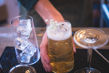Bartender in front of beautiful row of different coloured alcohol cocktails on a party in a bar, martini, vodka, and others on decorated catering banquet table on open air event