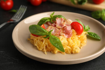 Tasty spaghetti squash with bacon and basil served on black table, closeup