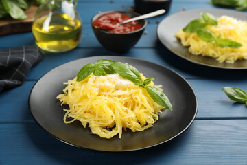Tasty spaghetti squash with basil and cheese served on blue wooden table