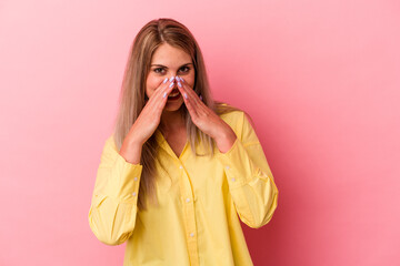 Young russian woman isolated on pink background saying a gossip, pointing to side reporting something.