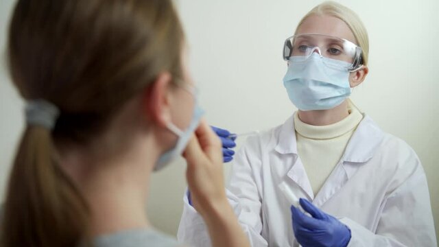 Hospital female employee at laboratory room closeup. PCR throat sample for corona virus test by medicine nurse indoors.