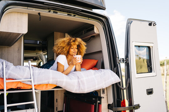 Black woman drinking hot beverage in caravan