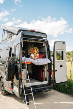 Black woman drinking hot beverage in caravan