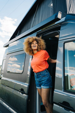 Happy black female traveler in van doorway