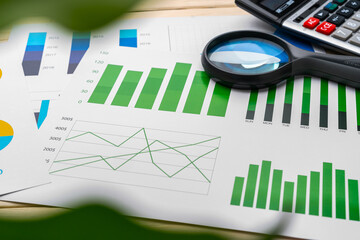 Obraz premium Business graphs and magnifying glass on table