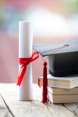 Close-up selective focus of a graduation cap or mortarboard and diploma degree certificate put on table - obrazy, fototapety, plakaty
