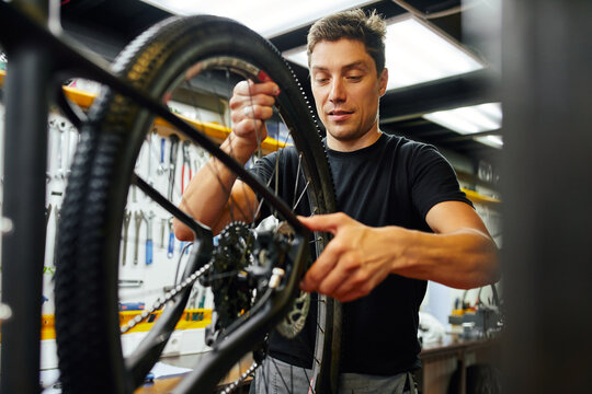 Man fixing bicycle wheel in garage - Powered by Adobe