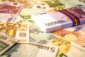 A pack of European currency lies on the background of the Euro
