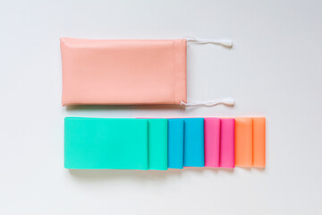 Flat lay of colorful resistance bands with storage pouch on white background. Sports or fitness equipment. 
