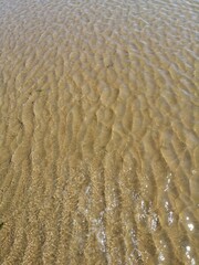 Wet sand surface ocean wave water ripples