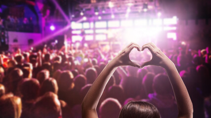 Love to music. Female heart shaped hands and crowd or audience at live music concert